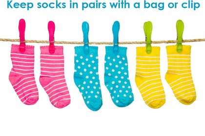 pink blue and yellow socks hanging by pegs on rope
