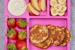 Pancakes on a pink tray with fruit and yoghurt